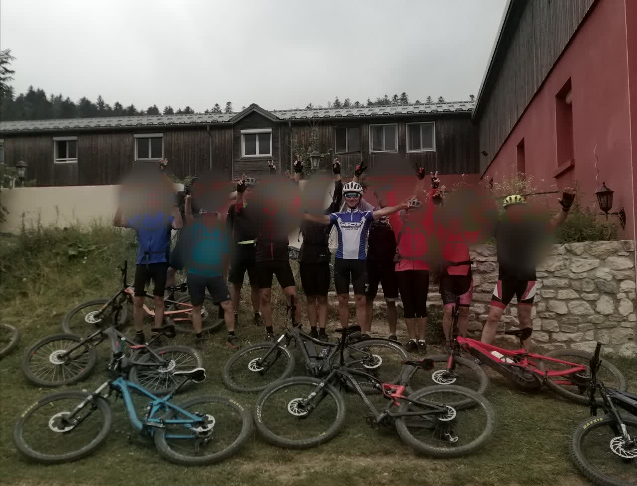 Groupe de vététistes en VTT à assistance électrique posant devant un gîte dans le Vercors, visages floutés